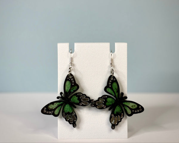 Butterfly-shaped earrings on a white card with a gray background