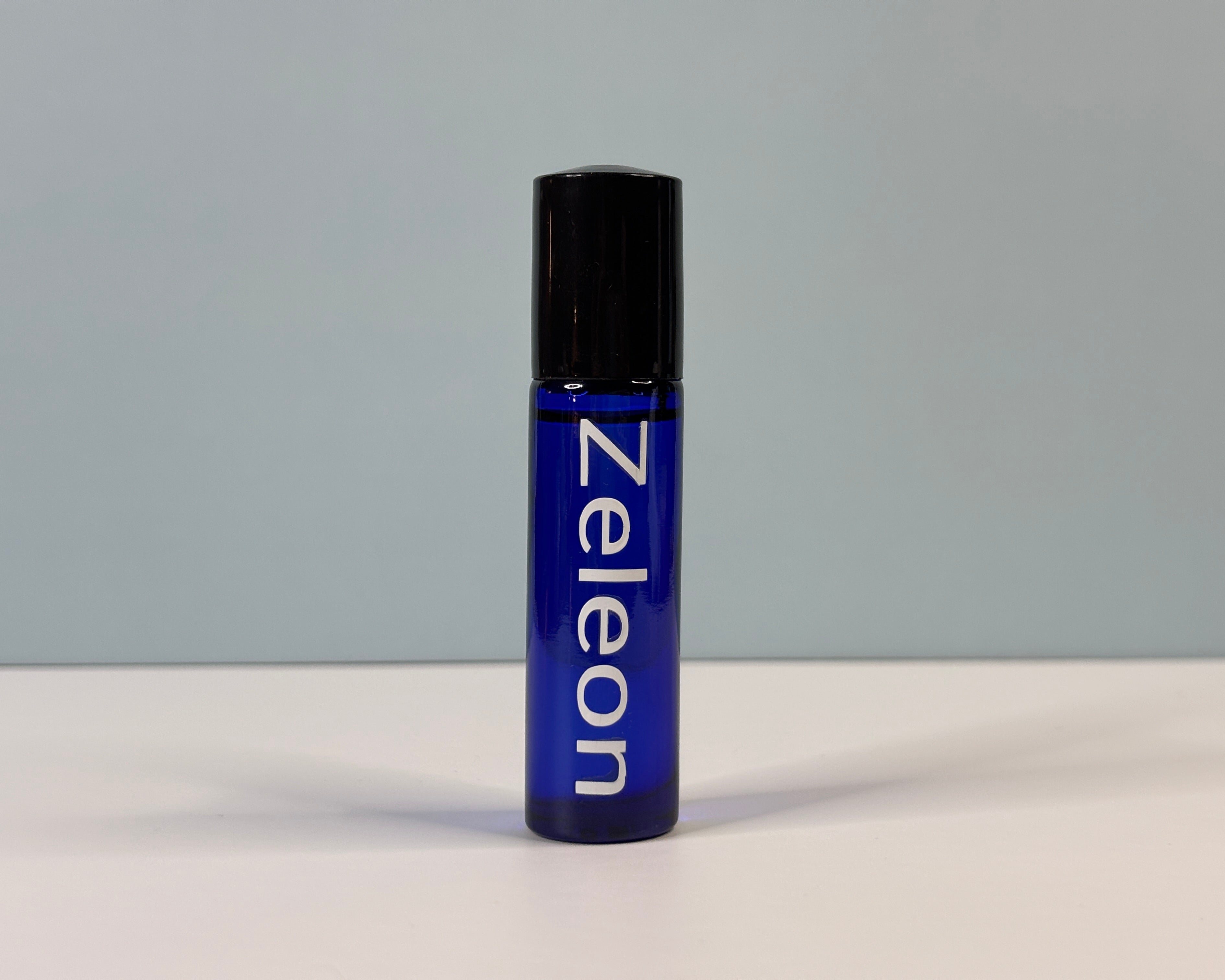 Blue rollerball bottle with black cap on a gray background