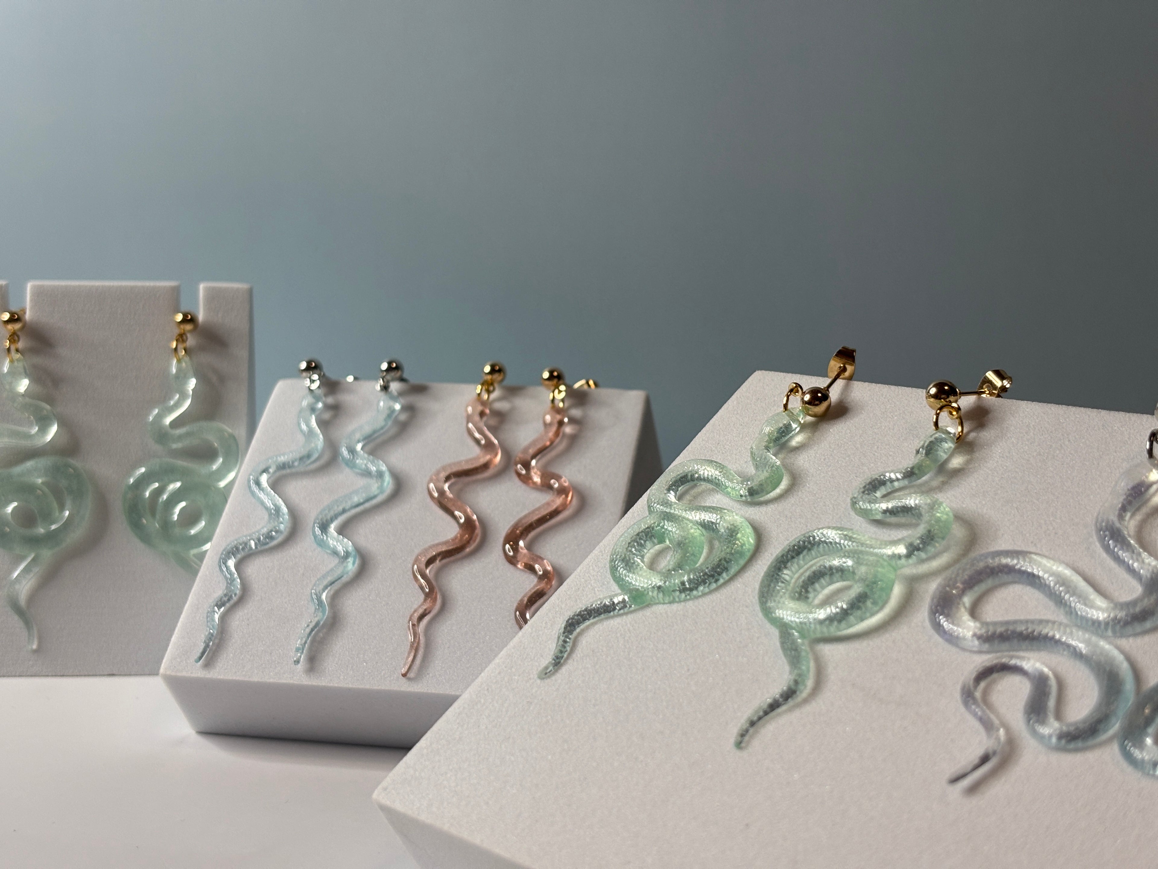 Snake-shaped earrings on display with a neutral background