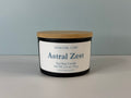 Astral Zest soy wax candle by Nova Girl Corp in a matte black jar with a bamboo lid, labeled with scent name and net weight 2.5 oz