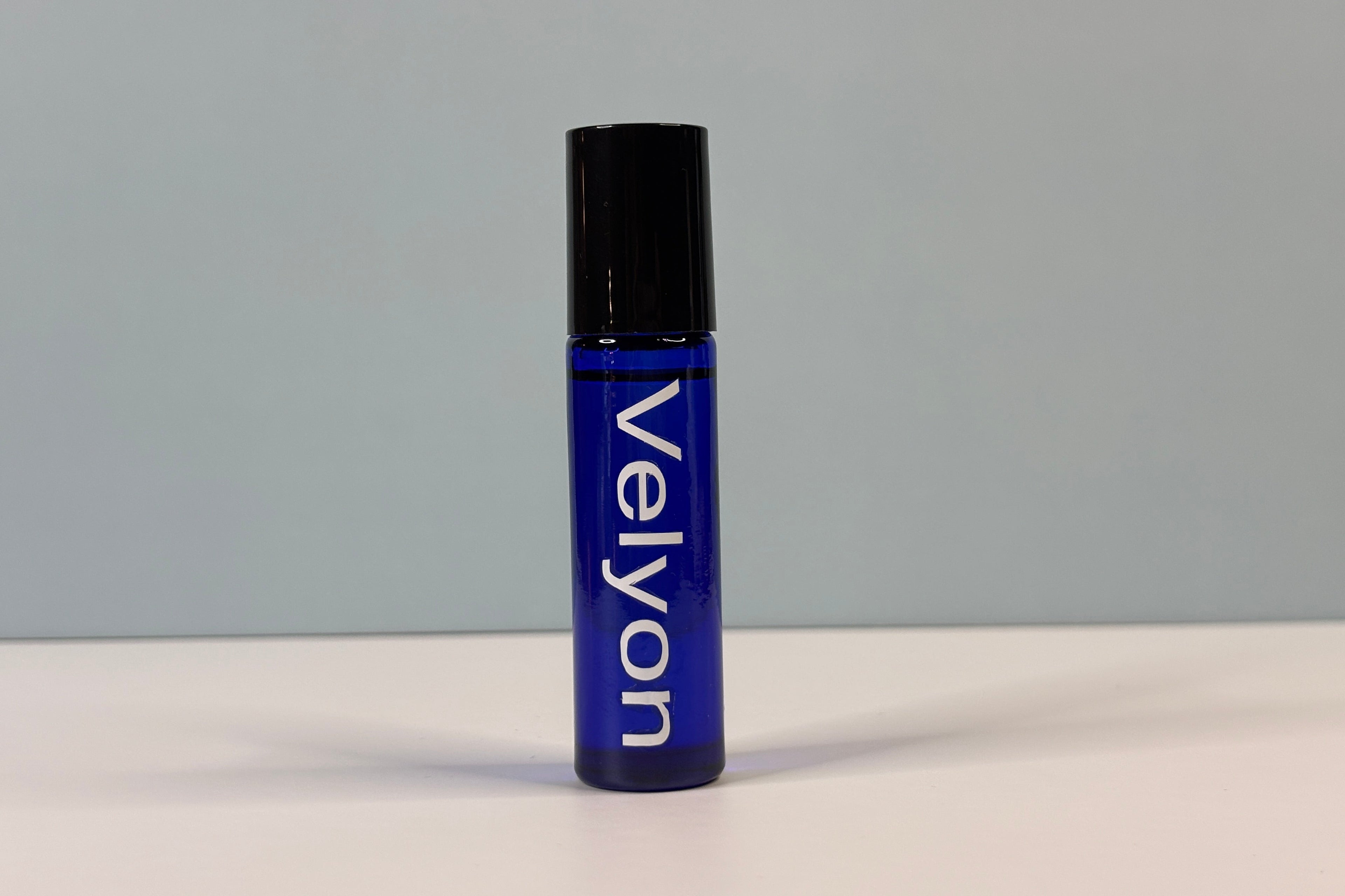 Blue rollerball bottle with black cap on a gray background