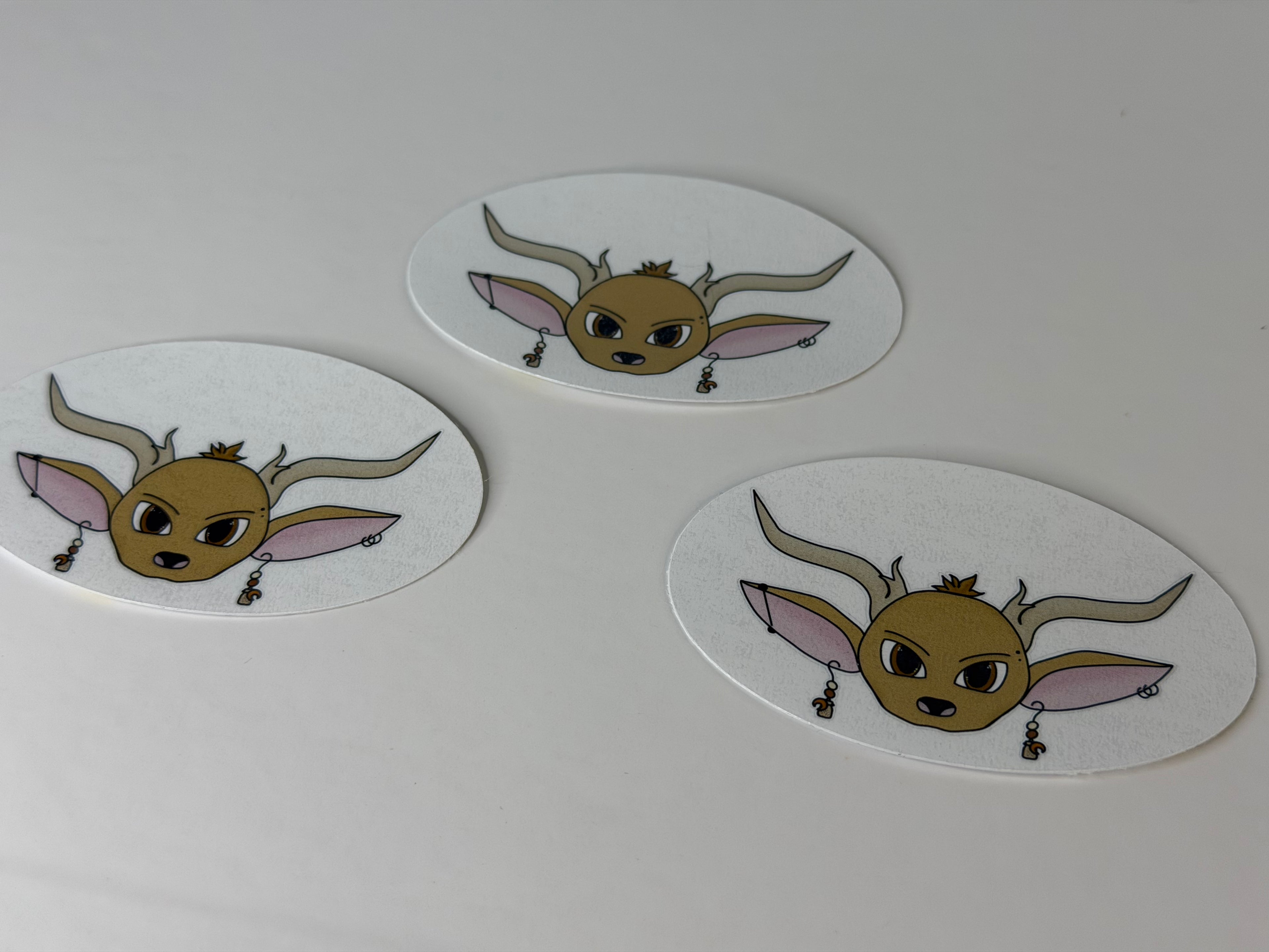 Three oval-shaped stickers with cartoonish animal face designs on a white background.